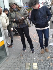 People including woman (on left) wearing a blue headscarf observing the Stolpersteine cleaning action © Irit Dekel 