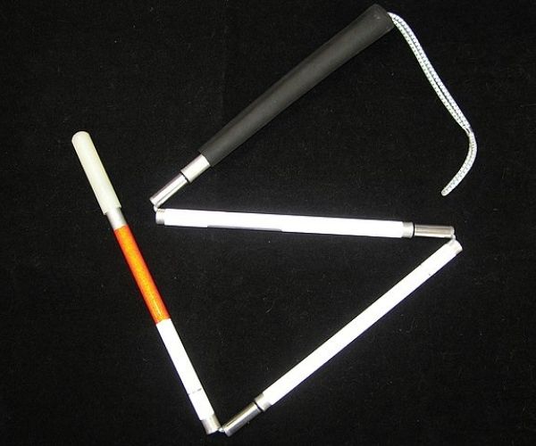 Photograph of a white cane semi-dismantled on a black background