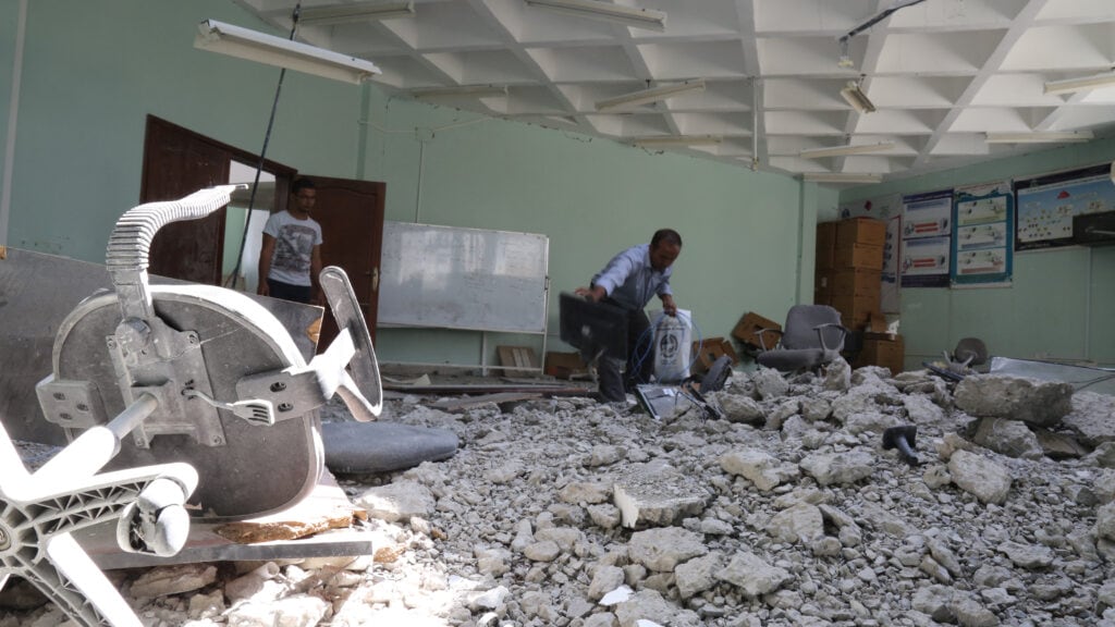 Two Yemenis stand amidst rubble in a destroyed classroom at Yemen's Taiz University in April 2016. Credit: akramalrasny / Shutterstock