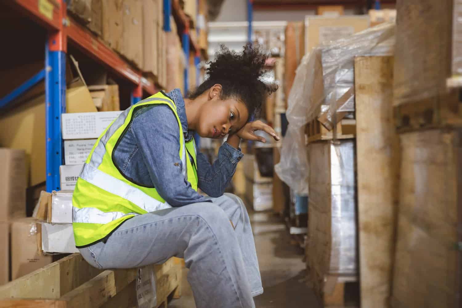 Female warehouse worker sitting and looking tired