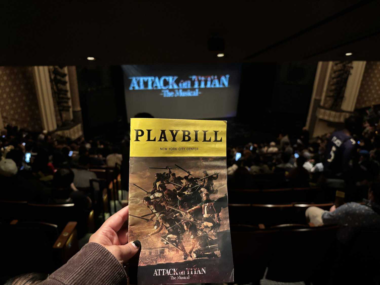 Photograph of hand holding playbill for ATTACK ON TITAN