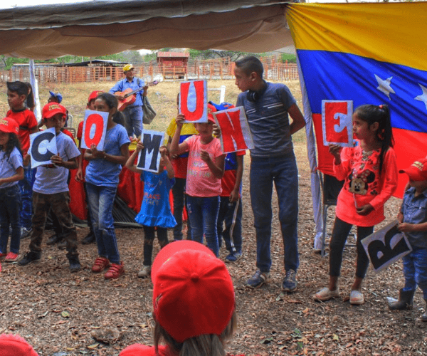 Group of children holds signs in support of El Maizal Commune.