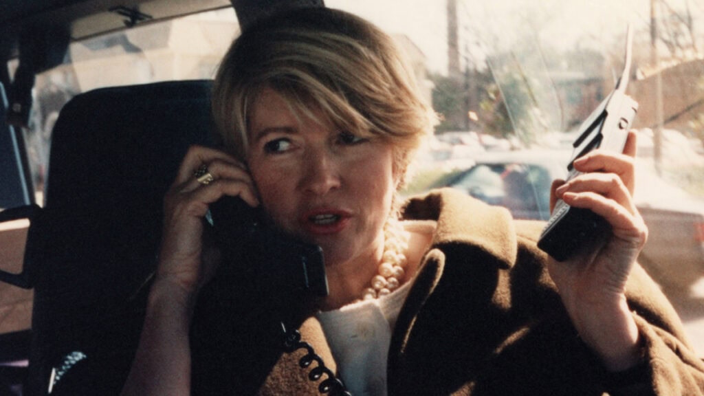 Blonde woman in car holding two cell phones