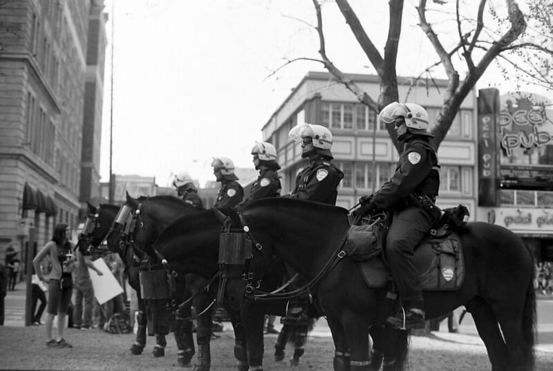 Black and white photograph of line of Montreal police wearing helmets and sitting on horseback