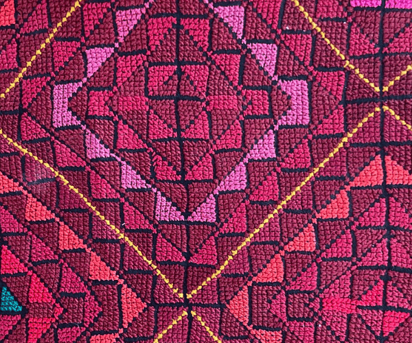 Close up photograph of pink embroidery in a chevron-based geometric design