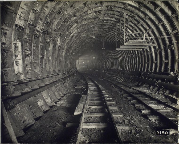 Black and white photograph of the interior of a large train tunnel under construction