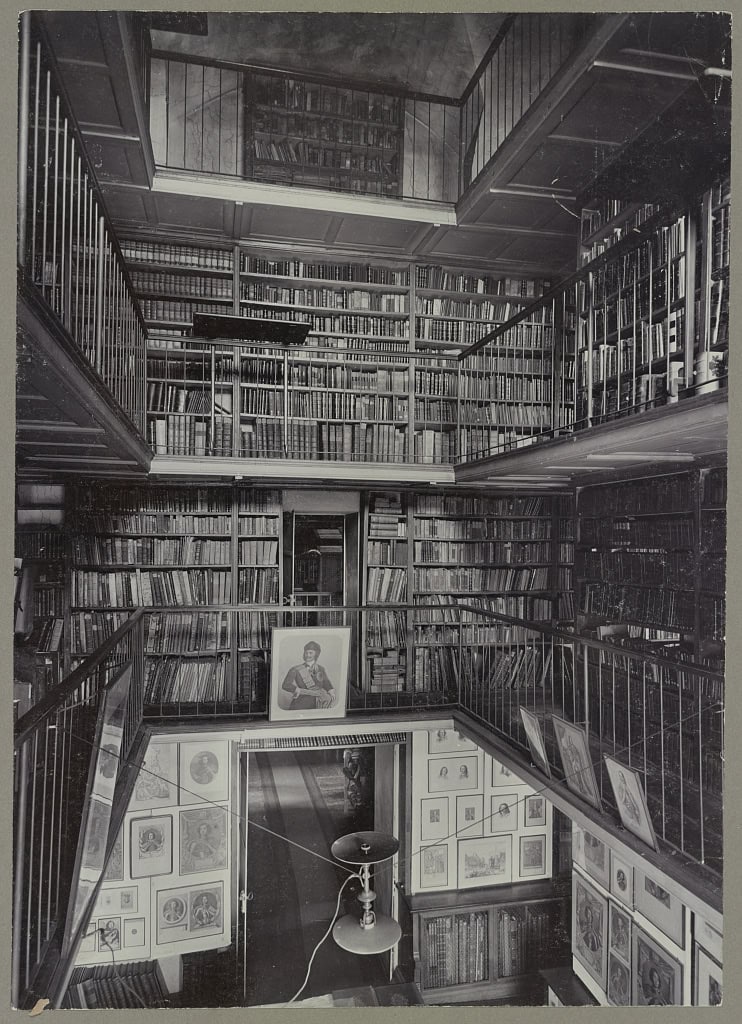 Photograph shows several levels of books and framed portraits at the Imperial Public Library, now National Library of Russia.