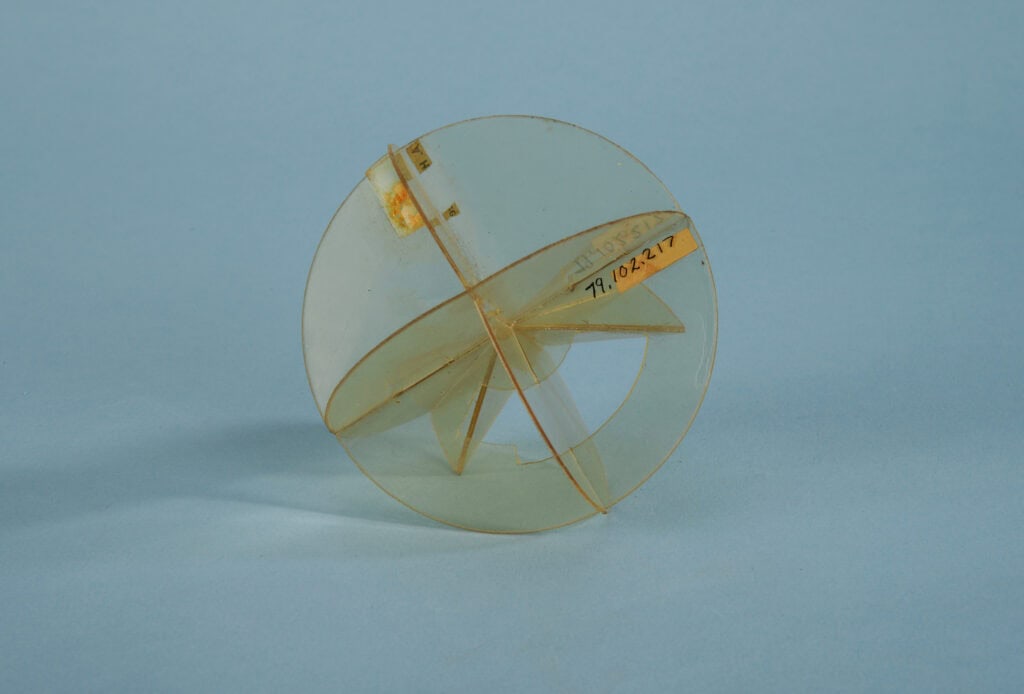 A cut-and-glued transparent plastic model from 1943 shows two perpendicular spherical discs (a representation of the equator) and a meridian disc of a sphere.