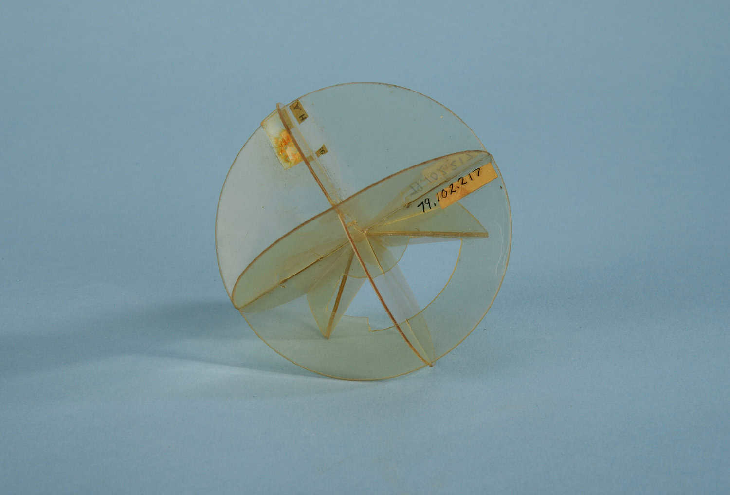 A cut-and-glued transparent plastic model from 1943 shows two perpendicular spherical discs (a representation of the equator) and a meridian disc of a sphere.