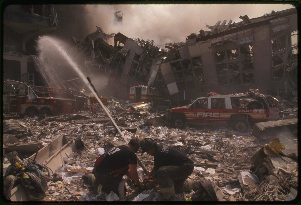 Two rescue workers direct a firehose at the ruins of the World Trade Center following the 9/11 terrorist attacks