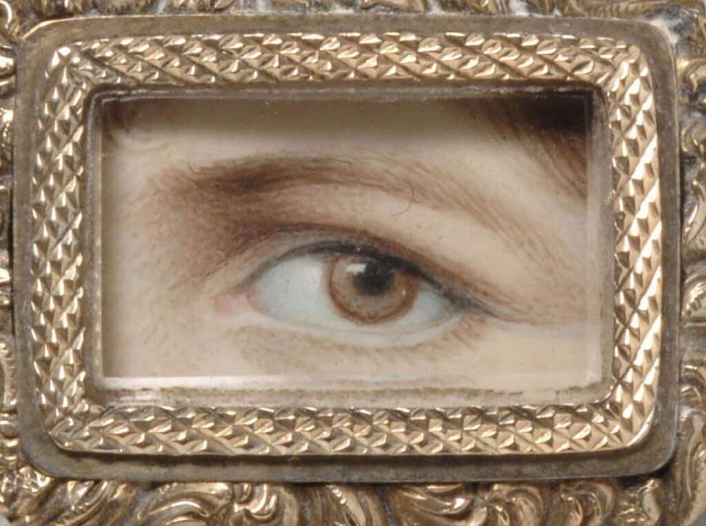 A miniature painting of a left eye set on a golden brooch.