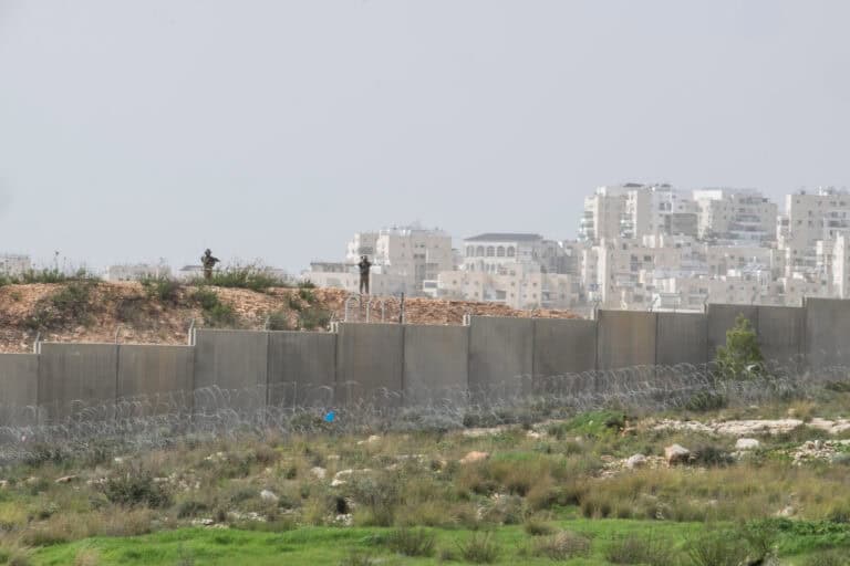 Two Israeli soldiers patrol along a concrete barrier in the West Bank