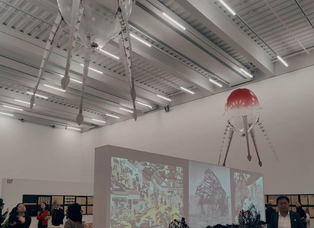 Photograph of gallery ceiling occupied by hovering mechanical objects with a jellyfish-like shape